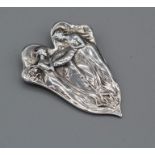 An unmarked white metal Art Nouveau style brooch depicting two nymphs/fairies peering into an open