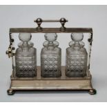 An Edwardian EPNS three bottle Tantalus by Daniel and Arter, Birminham. Numbered G7028, 37cm wide,