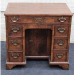 A reproduction George II style walnut kneehole desk, the crossbanded rectangular top over an