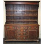 A late 18th century oak tall dresser, the boarded rack with three open shelves over four graduated