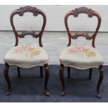 A pair of Victorian walnut salon chairs, each having florally carved rail and splat, woolwork