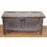 A late 17th century oak coffer, three panel top over later carved frieze and two panel front