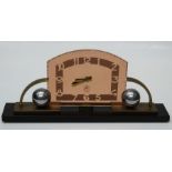 An Art Deco mantle timepiece, the narrow oblong slate base having a pink glass stylized frame with a