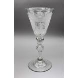 An Edwardian glass goblet, the conical bowl etched with cupid forging arrows, on a knopped bubble