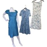 6 1950s dresses in shades of blue and green to include an aqua dress with polka dots, a belted day