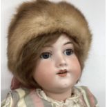 German Good Bisque head doll 23” 390 AM child doll in cream and plaid attire. With fur cap (1)