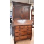 George III oak bureau/bookcase with panelled doors above a drop-down writing top. It has a