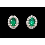A pair of emerald and diamond 18ct white gold cluster stud earrings, comprising central oval mixed