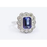 A tanzanite and diamond platinum cluster ring, comprising a central octagonal step cut tanzanite