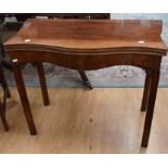 An early 19th Century mahogany serpentine card table with folding top, on fluted legs with foliage