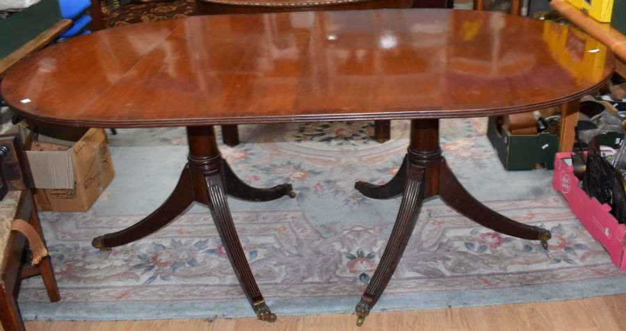 A Regency style mahogany extending dining table, on twin pedestal supports with reeded columns,