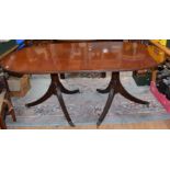 A Regency style mahogany extending dining table, on twin pedestal supports with reeded columns,
