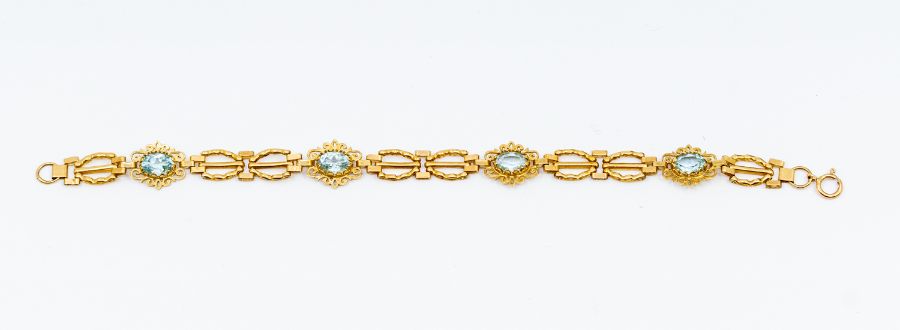A blue topaz and 9ct gold bracelet, comprising alternate oval claw set blue topaz and gate style