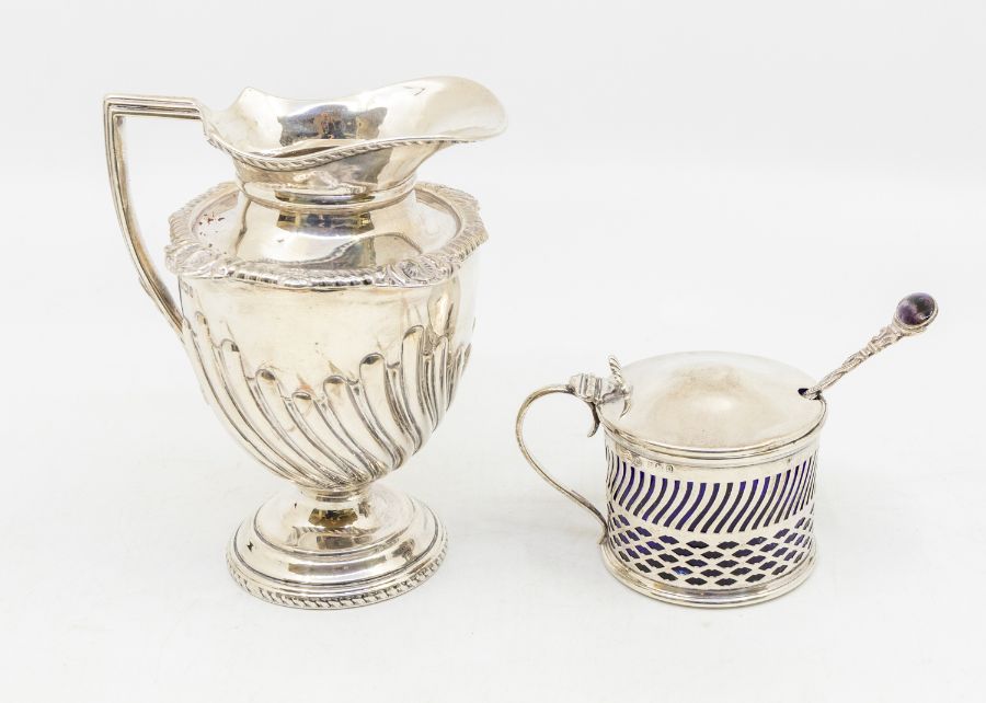 A Georgian style silver cream jug, ovoid shape with gadroon lower section, hallmarked by James