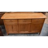 A late 20th Century Ercol sideboard in teak of three drawers above three cupboards, along with a