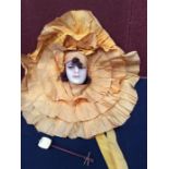1920s wax doll's head, with hand-painted face, surrounded by orange fabric