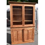 A Victorian stripped pine kitchen unit with two glazed doors to reveal three storage shelves above