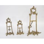 A collection of three antique brass table easels, various sizes