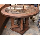 An old wooden cartwheel with cast rim converted into a glass topped table with axle used as base