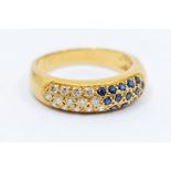 A diamond and sapphire 18ct gold ring, comprising a domed top grain set to one side round