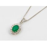An emerald and diamond 18ct white gold cluster pendant, comprising a central oval mixed cut emerald,