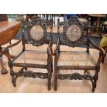 Pair of reproduction Jacobean carved wooden armchairs with cane seat and back (one partly