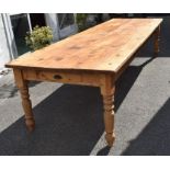 A very large stripped pine refectory/kitchen table with side and end drawers, on turned legs,