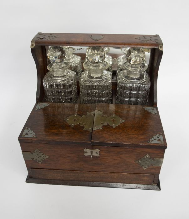 An early 20th Century tantalus in oak, having four original glasses and two later additions.