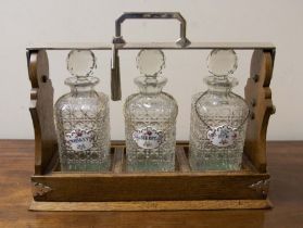 An early 20th Century silver plate mounted oak tantalus together with three cut glass sprit