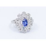 A natural sapphire and diamond 18ct white gold cluster ring, comprising a central claw set oval pale