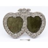 An early 20th Century possibly American silver double heart shaped frame, ribbon tied chased