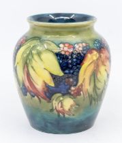 A Moorcroft leaf and berry patterned vase, signed, approx. 12cm high. Condition: good