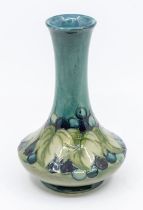 A Moorcroft leaf and berry, dark blue design, thin long necked vase, signed, approx. 15cm high.