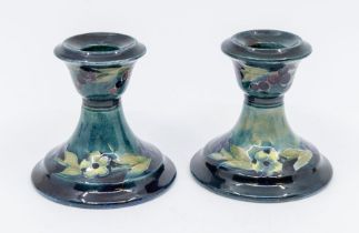 A pair of Moorcroft dark blue Berry pattern candlesticks, approx. 8cm high. Condition: good