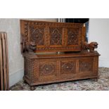 A Victorian carved oak Monk’s bench, with adjustable panelled back/table top, lion supports on box