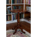 A late Victorian mahogany lamp or wine table, circular, on a turned stem with four hipped and swept