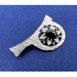 A Platinum, sapphire and diamond brooch in the form of a "p" or "d" created from an engagement