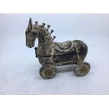 A 20th century Sino-Tibetan carved wooden figure of a horse on wheels, the top hinged and opening to