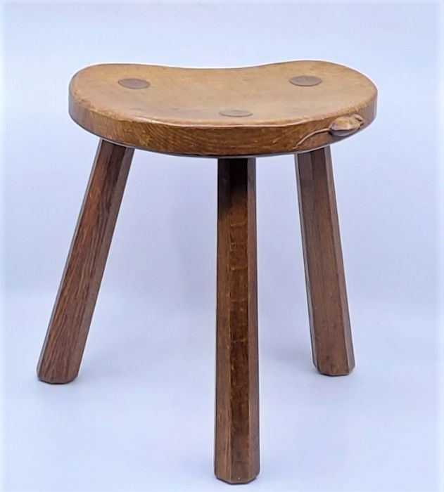 A Robert "Mouseman" Thompson oak three legged stool, the dished kidney shaped seat with carved mouse