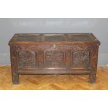 An early 18th century oak coffer, the three panel top over carved frieze and anthemion decorated