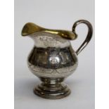 A late 19th century Russian silver pedestal cream jug of bellied form with florally chased band,