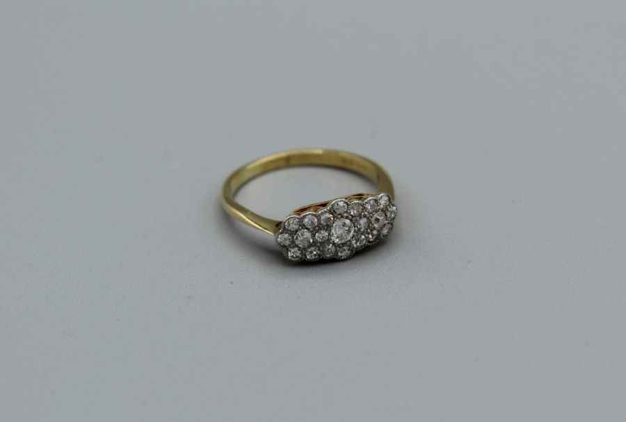 An East to West diamond cluster ring set in yellow metal, stamped 18ct, size L1/2, gross weight