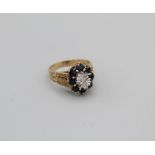 A sapphire and diamond cluster ring with textured and floral band, size Q, gross weight