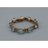 An aquamarine set bracelet in yellow metal, the stones interspaced with quatrefoil flowers, gross