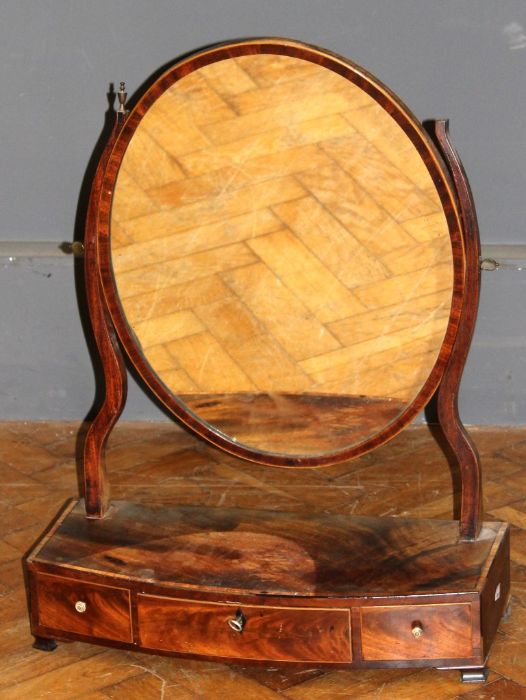 A George III mahogany toilet mirror, the oval plate within shaped horns with urn finials, on a bow