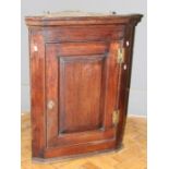 A George III mahogany wall mounting corner cupboard, the moulded cornice over a fielded panel door