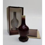 A Chinese sang de boeuf bottle vase of small size, 19th century, together with hardwood stand and