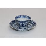 A Chinese blue and white tea bowl and saucer, Kangxi, decorated with reserved bands of floral forms.