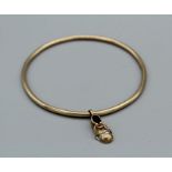 A yellow metal bangle, unmarked, with an unlaced shoe charm, hallmarked 9ct gold, set with two melee