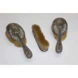 A set of sterling silver brushes comprising a pair of hairbrushes and a clothes brush. The